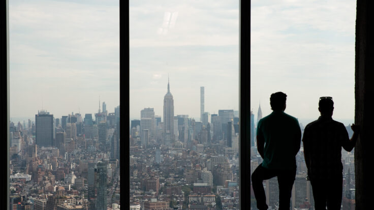 Two men look out the window from One World Trade Center